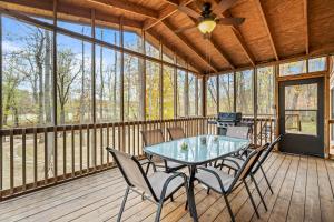 a screened in porch with a table and chairs at Sleepy Creek - Hot Tub, Pet Friendly, Creekside, Grill, Wifi, Fire Pit, Deck, Screen Porch, Family Friendly, Fishing, View, Games in Berkeley Springs