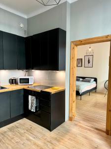 a kitchen with black cabinets and a room with a bed at Melrose Place in Helsinki