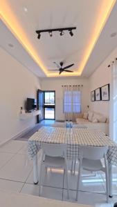 a white living room with a table and chairs at Homestay Dataran Tikam Batu in Sungai Petani