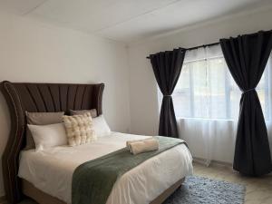 Schlafzimmer mit einem großen Bett und schwarzen Vorhängen in der Unterkunft Hippoville in Mbabane