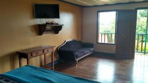 a bedroom with a couch and a tv in a room at Chales das Andorinhas in Lavras Novas