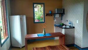 a kitchen with a table and a refrigerator at Chales das Andorinhas in Lavras Novas