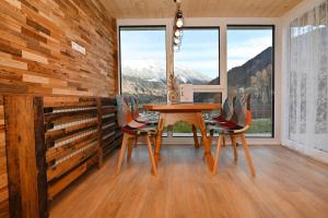 a dining room with a table and chairs and windows at Rundblick 2 Gartenwohnung in Tschagguns +6 photos