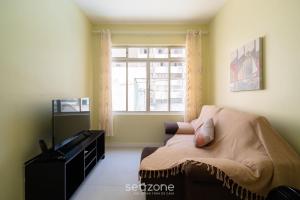 a living room with a couch and a window at Aptos completos com localização privilegiada no coração de Floripa – CSNs in Florianópolis