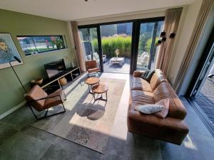ein Wohnzimmer mit einem braunen Sofa und Stühlen in der Unterkunft Villa in Balk with Private Jetty on Slotermeer in Balk