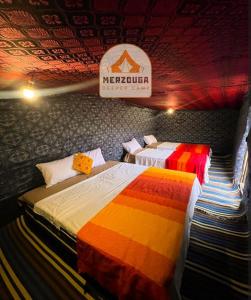 Zwei Betten in einem Zimmer mit einem Schild an der Decke in der Unterkunft Merzouga Deeper Camp in Merzouga + 101 Fotos