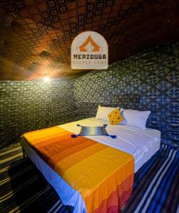 Bett in einem Zimmer mit Schild an der Wand in der Unterkunft Merzouga Deeper Camp in Merzouga