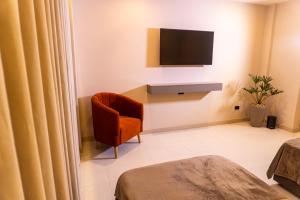 Una habitación con una silla y un televisor en una pared. en Hotel y Restaurante Mesón del Gitano, en Caucasia