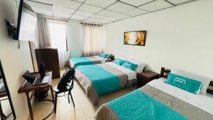 a hotel room with three beds and a desk at Hotel Suite Centro Bogotá in Bogotá