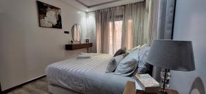 a bedroom with a bed with a lamp and a window at Central Marrakech Sunny Stay Poolside Apartment in Gueliz in Marrakech +21 photos