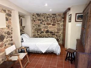 a bedroom with a bed and a stone wall at Sidrós Houses in Vila Nova