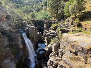 a waterfall on the side of a rocky mountain at Sidrós Houses in Vila Nova
