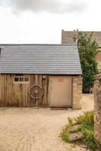 eine Scheune mit einem Rad an der Seite in der Unterkunft The Henloft Cotswolds Farm Stay With Pool in Lechlade