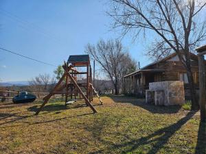 a playground in a yard next to a log cabin at Sommerwind Cabañas in La Estancia