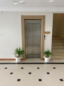 un hall d'entrée avec deux plantes en pot devant un ascenseur dans l'établissement شقق رحابة المكان للشقق المفروشه, à Al Kharj 1 autre photo