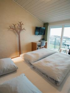 um quarto com duas camas e uma árvore na parede em Strandhotel Klinten em Rødvig