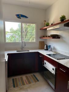 una cocina con fregadero y ventana en Jazmin Del Sol steps away from Playa Potrero !!, en Potrero