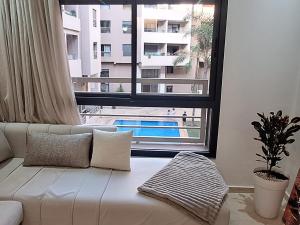 a white couch in a living room with a large window at Appartement Moderne Poolside Gueliz centre Sun PS4 & Wi-Fi in Marrakesh