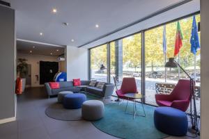 レサ・ダ・パルメイラにあるホリデイ イン エクスプレス ポルト エクポノールのソファと椅子と窓のあるリビングルーム