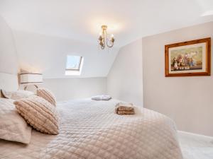 a white bedroom with a bed and a picture on the wall at Wheelwright's Cottage in Yeaveley