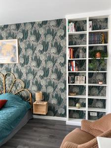 a bedroom with a book shelf with green leaves wallpaper at L'Ecrin Angevin in Le Plessis-Grammoire