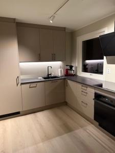 una cucina con mobili bianchi, un lavandino e una finestra di Langhaugen a Kabelvåg