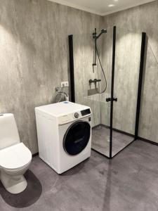 a bathroom with a toilet and a shower with a washing machine at Langhaugen - Kabelvåg in Kabelvåg +16 photos