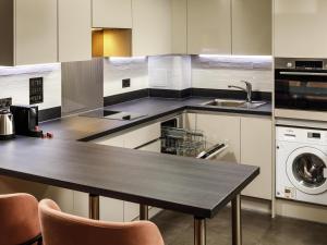 eine Küche mit einem Tisch und einer Waschmaschine in der Unterkunft Aparthotel Adagio London Sutton Point in Sutton