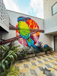a mural of a colorful bird on the side of a building at Habitat Ochentayuno in Medellín