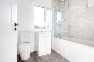 a bathroom with a toilet and a sink and a window at The ChurchHill in East Barnet