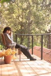 Ein Mann, der auf einem Stuhl sitzt und auf einem Handy spricht in der Unterkunft San José del Pacífico- Cabañas Camino al Cielo 2 in San Mateo Río Hondo