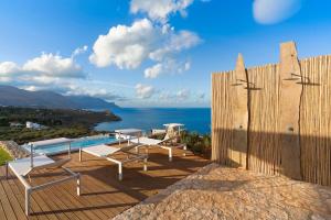 a patio with a pool and chairs and the ocean at Villa Corallo Cala Bianca in Castellammare del Golfo