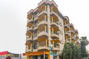 a tall yellow and white building on a street at Hotel O Bideshini Hotel in Tarapith