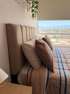 un lit avec des oreillers assis à côté d'une fenêtre dans l'établissement innovador departamento cercano a mall y carretera, à Rancagua