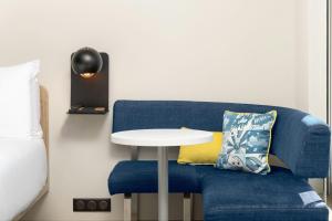 un divano blu con un tavolo bianco accanto a un letto di Aloft Strasbourg City Centre a Strasburgo