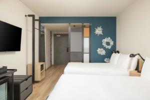 una camera d'albergo con due letti e una TV a schermo piatto di Aloft Strasbourg City Centre a Strasburgo