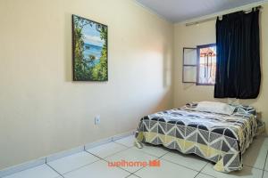 ein Schlafzimmer mit einem Bett und einem Bild an der Wand in der Unterkunft Casa em Cabo Frio com Churrasqueira e Praia in Barra de São João