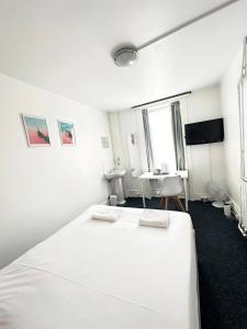 a white bedroom with a bed and a desk at Number 75 in Brighton & Hove