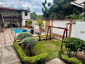 a garden with a swing and a house at Hotel Boutique Colonial Cartago in Cartago