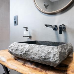 La salle de bains est pourvue d'un grand lavabo en pierre et d'un miroir. dans l'établissement ZenArden - Ninglinspo Valley view Lodge, à Aywaille