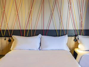 阿雷格里港ibis Styles Porto Alegre Moinhos de Vento的一间卧室，有两张床和一面带有彩色条纹的墙壁 更多81张照片