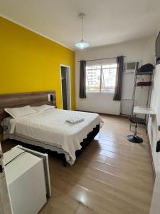 a bedroom with a bed and a yellow wall at Exito in Guarulhos
