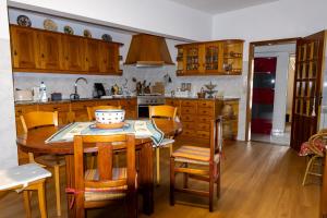 a kitchen with wooden cabinets and a table and chairs at Edu Stay Mondego in São Pedro de Alva
