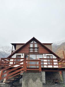 Casa de madera grande con balcón y montañas en old white house, en Kazbegi