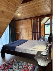 Un dormitorio con una cama y una pared de madera. en old white house, en Kazbegi