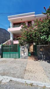 ein rosa Haus mit grünem Zaun und Blumen in der Unterkunft Kaza Manata in Praia
