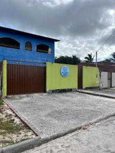 ein blau-grünes Gebäude mit einem Zaun in der Unterkunft Casa nos Lençóis Maranhenses-Santo Amaro MA in Santo Amaro