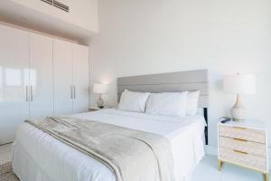 a white bedroom with a large bed and two lamps at Arubas Life 303 in Noord +54 photos