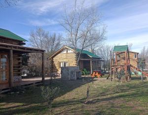 a log cabin and a playground in a yard at Sommerwind Cabañas in La Estancia