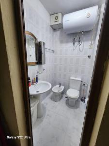 ein weißes Badezimmer mit Toilette und Waschbecken in der Unterkunft Cozy Home in Tirana